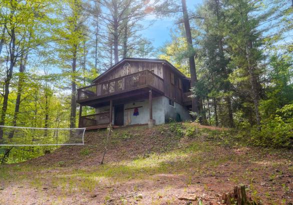 two strorey wood cottage with 2 levels of decks, sandy front and surrounded by trees.
