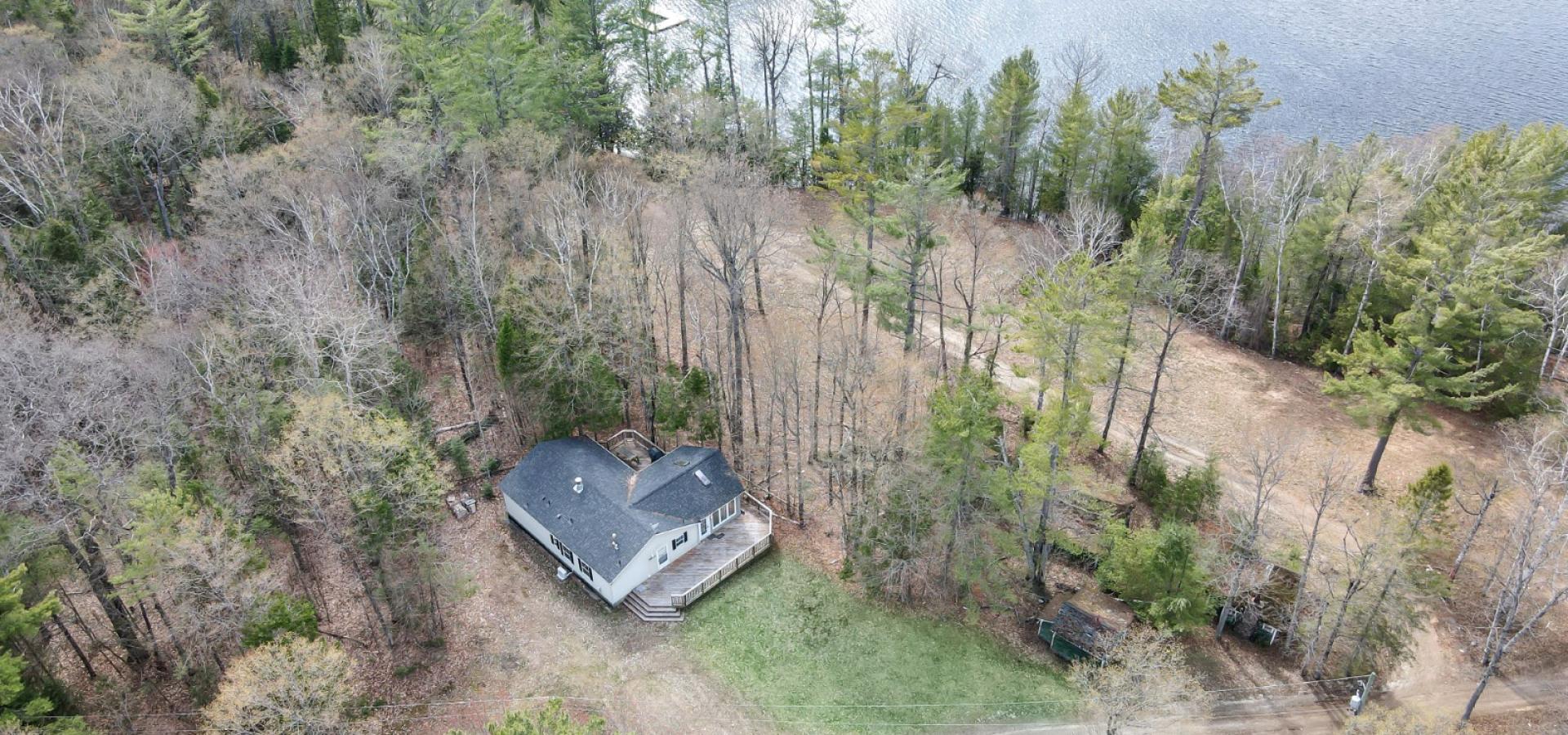 Aerial view of a home with trees surrounding it and facing the lake