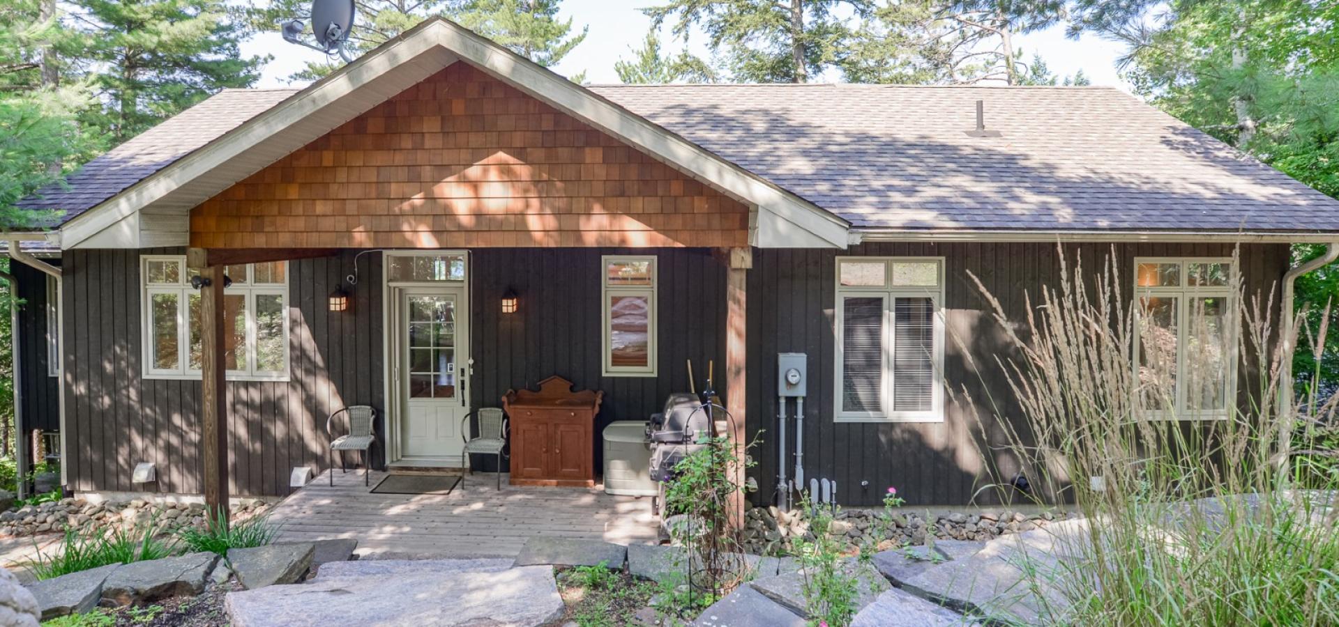 Dark grey cottage front with cedar wood peak on covered front door.