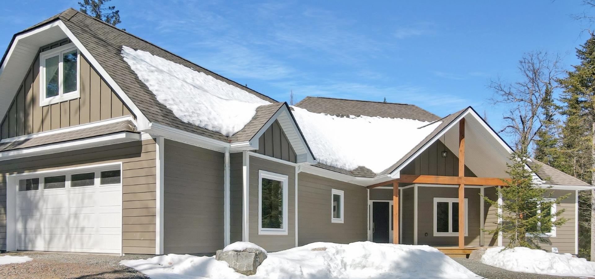 brown and white home with wood framing on porch and surrounded by snow.
