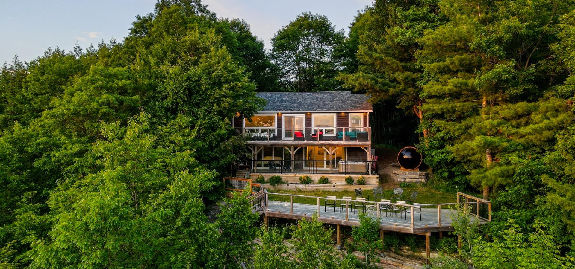 Cottage with two tier deck surrounded by trees. Lower level patio overlook Boshkung lake. 