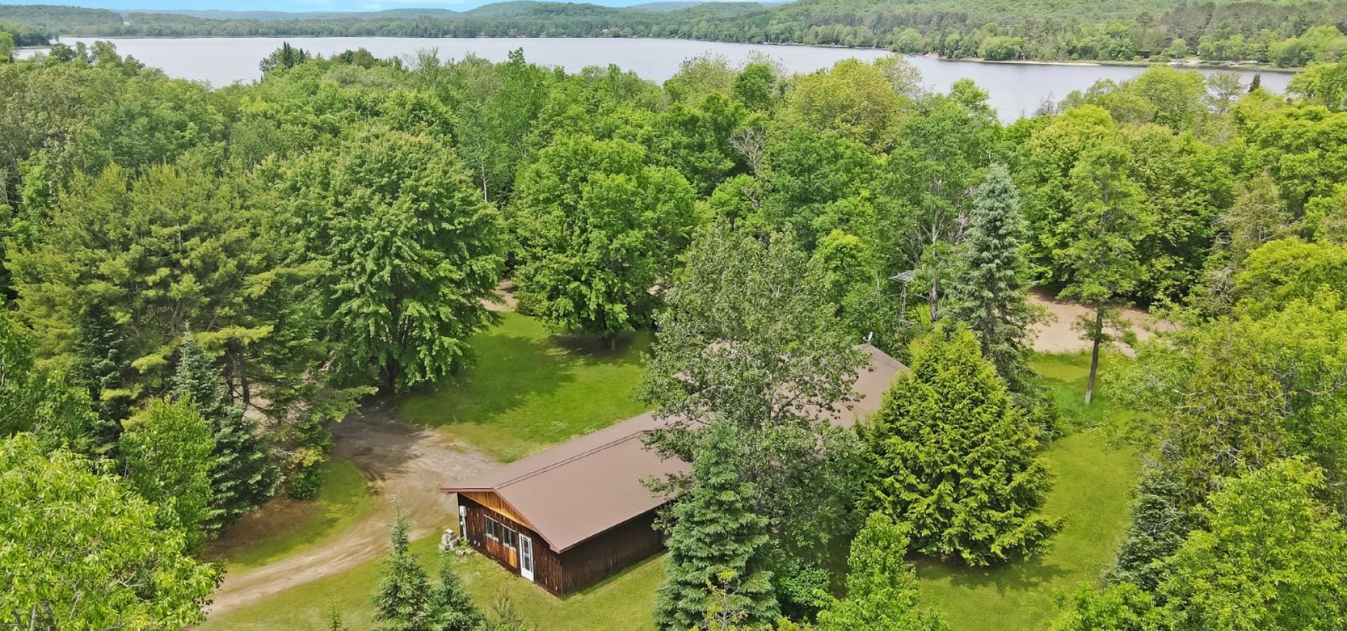 House surrounded by trees with a river leading to the lake.