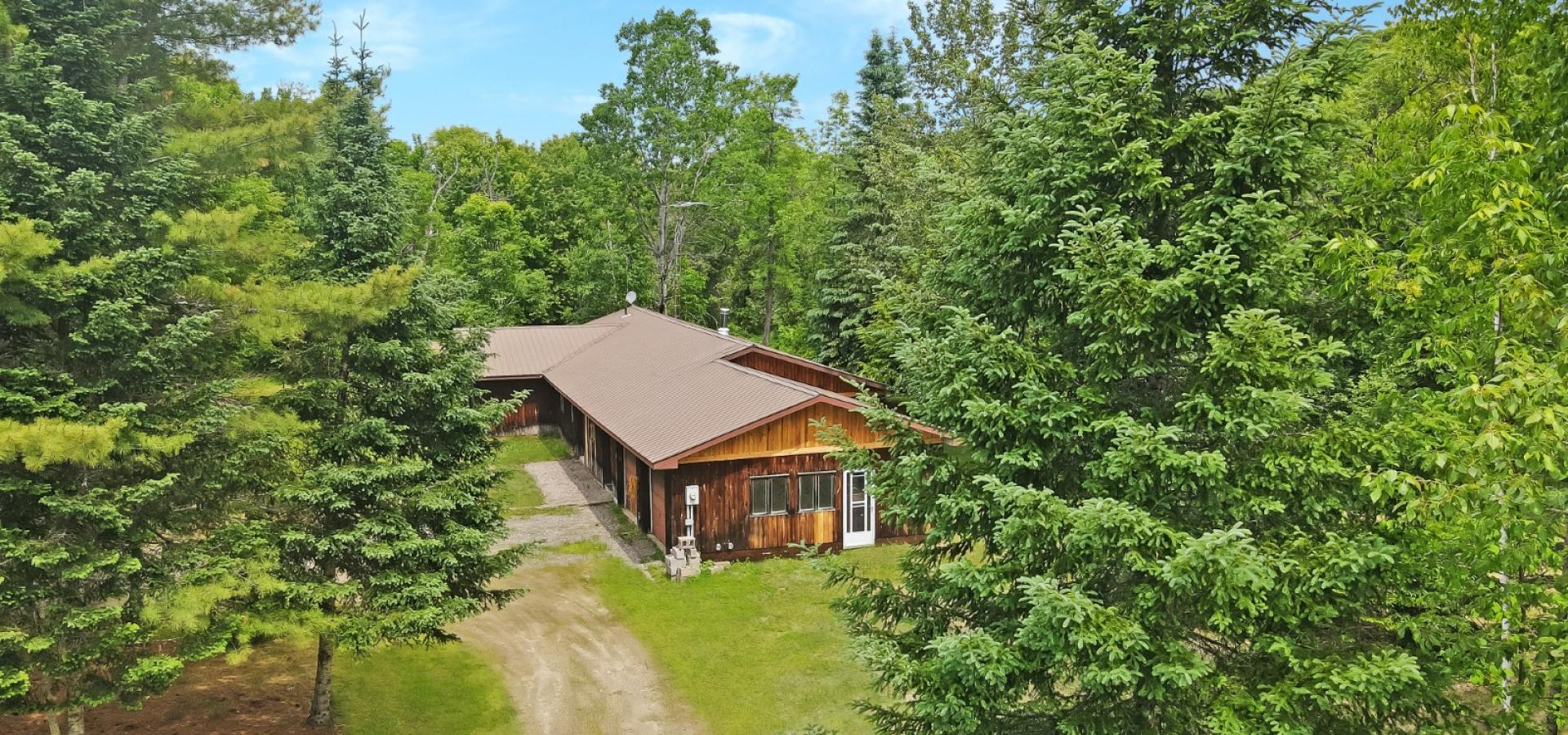 Aerial view of a cottage with trees around it