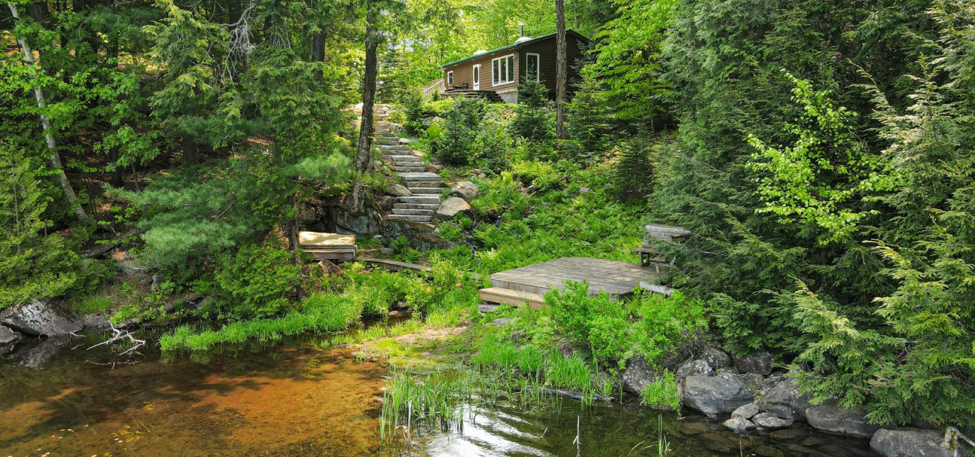 cottage on a hill with stairs up and water front