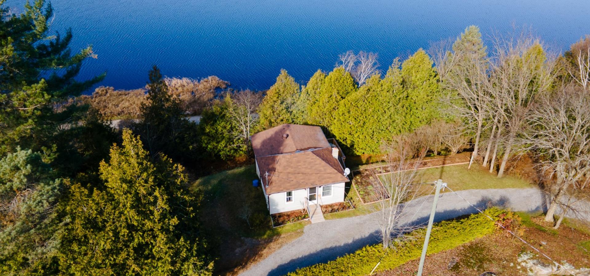 aerial view of a home surrounded by trees and a lake in the background