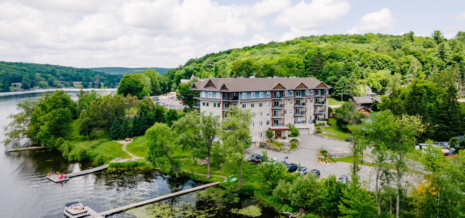 condo building surrounded by trees and a dock in the lake. 