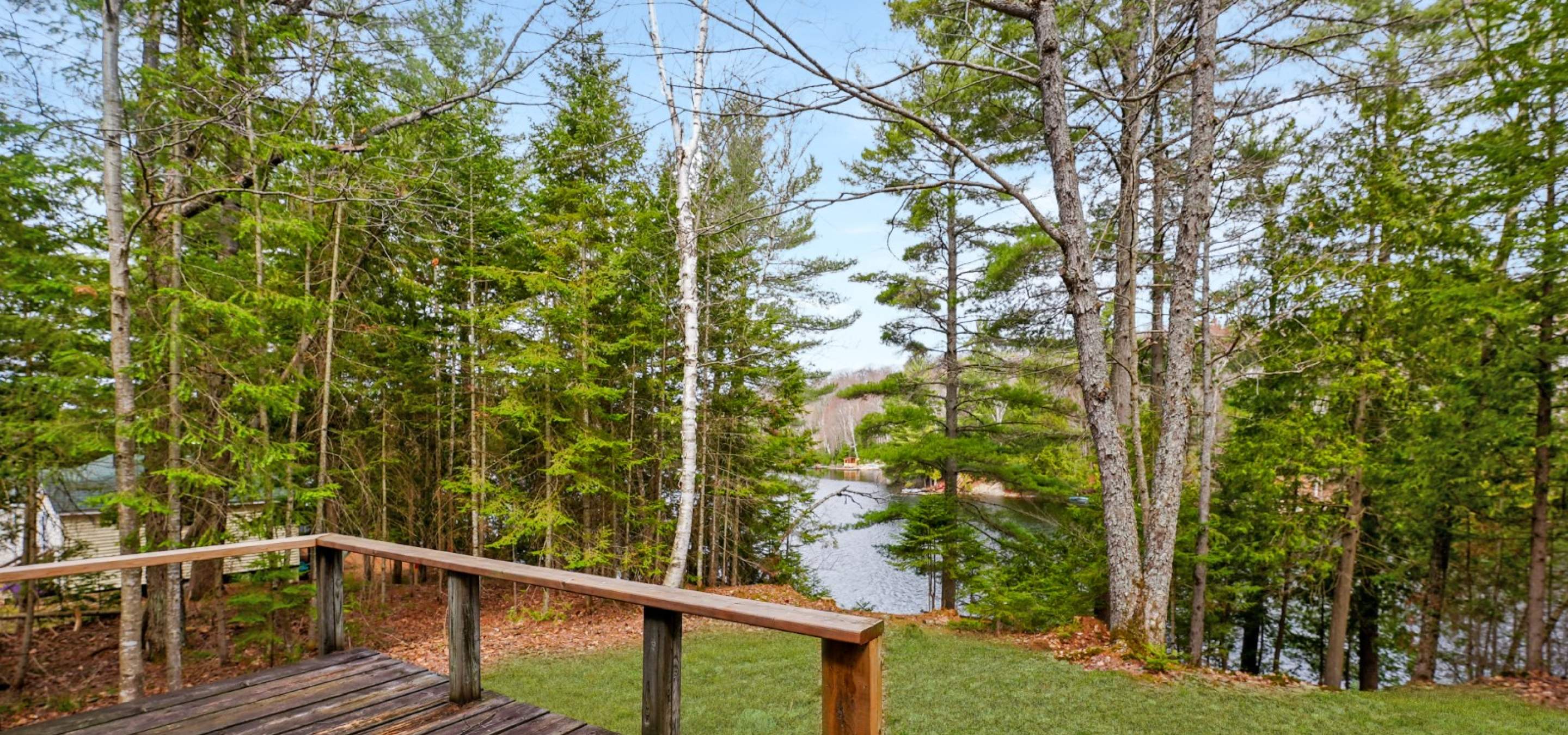 looking out towards the lake from a deck with trees obstructive the lake view. 
