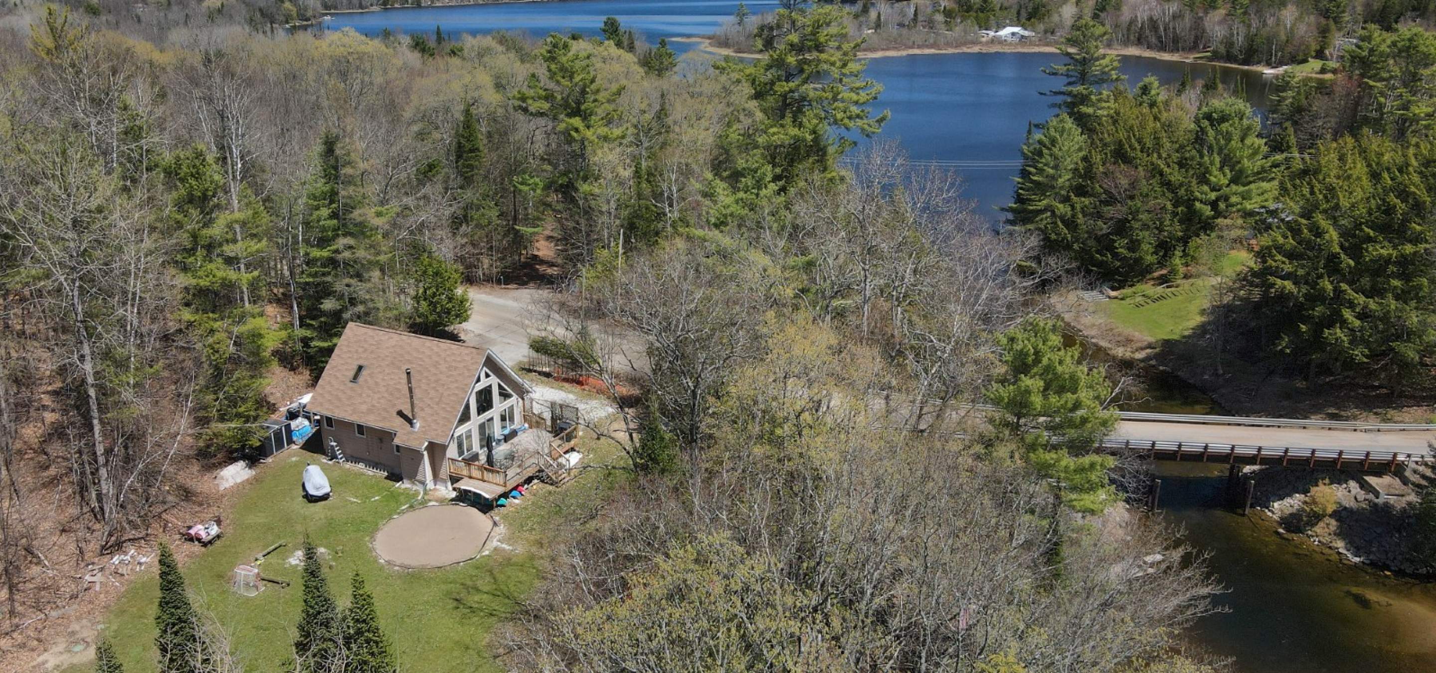 Aerial view of a property with trees, a road, a river and a lake in the background