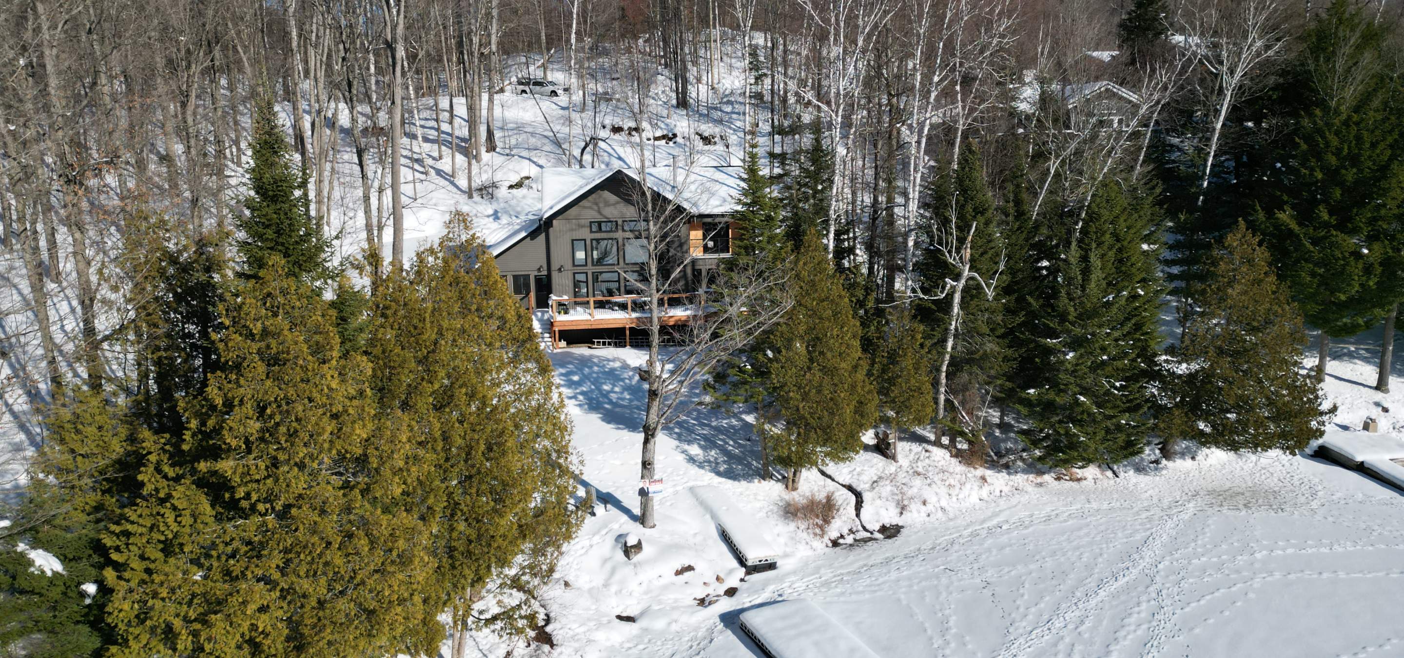 New cottage with a blanket of snow and surrounded by trees. 