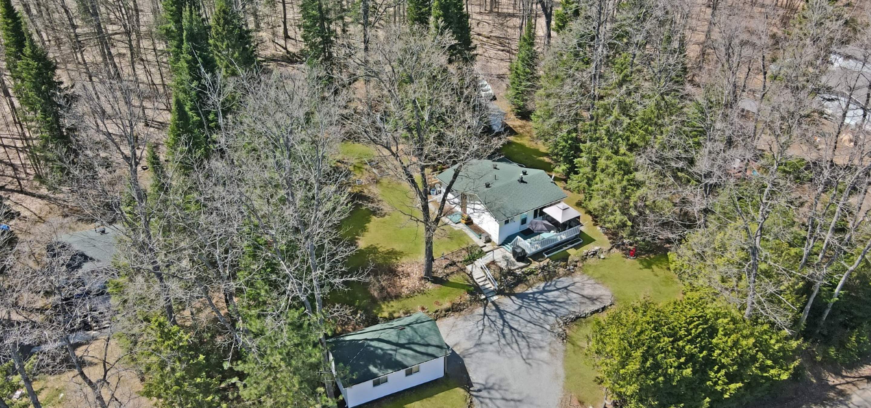 aerial view of a home surrounded by grass and tress.
