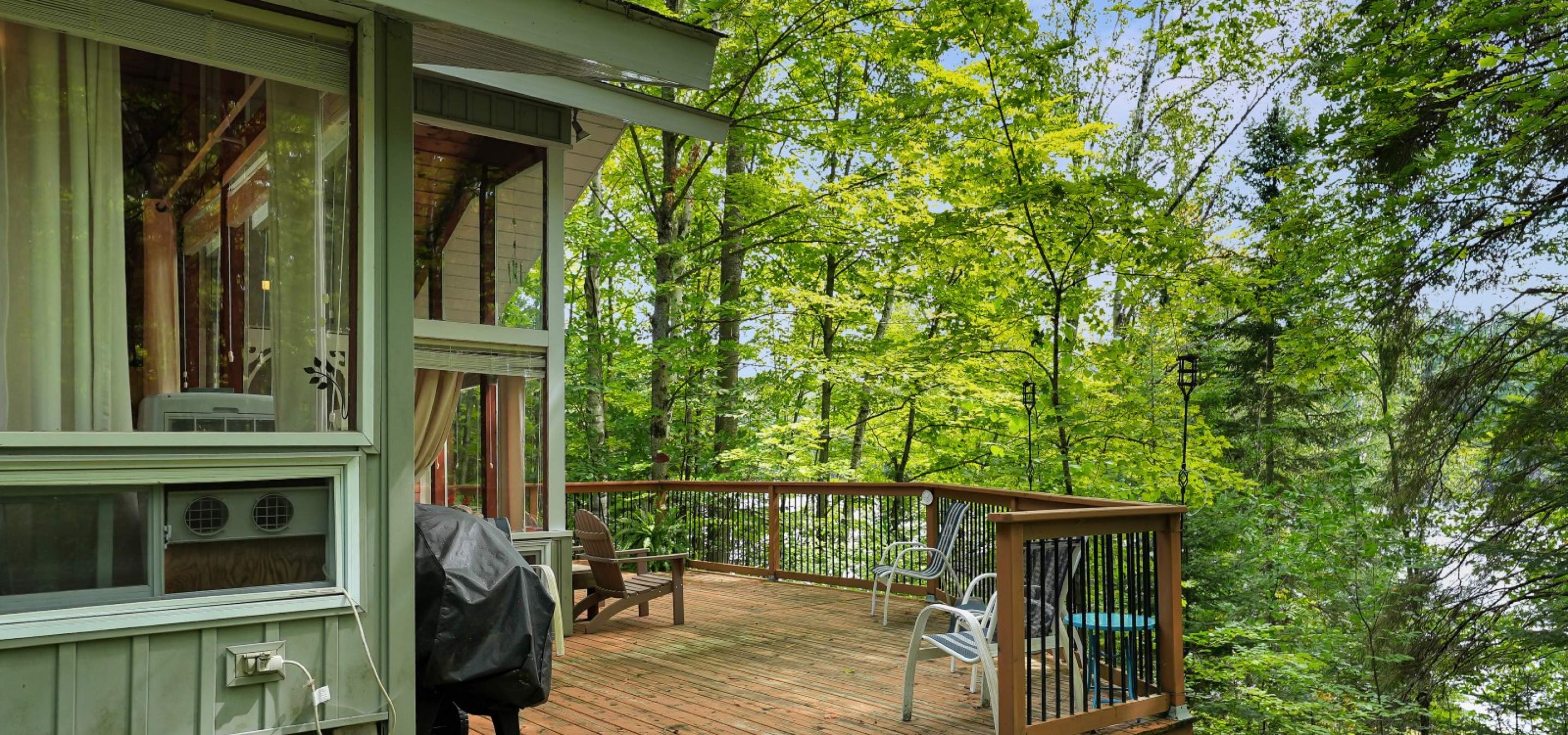 showing the view from the cottage and the deck looking towards the lake and trees