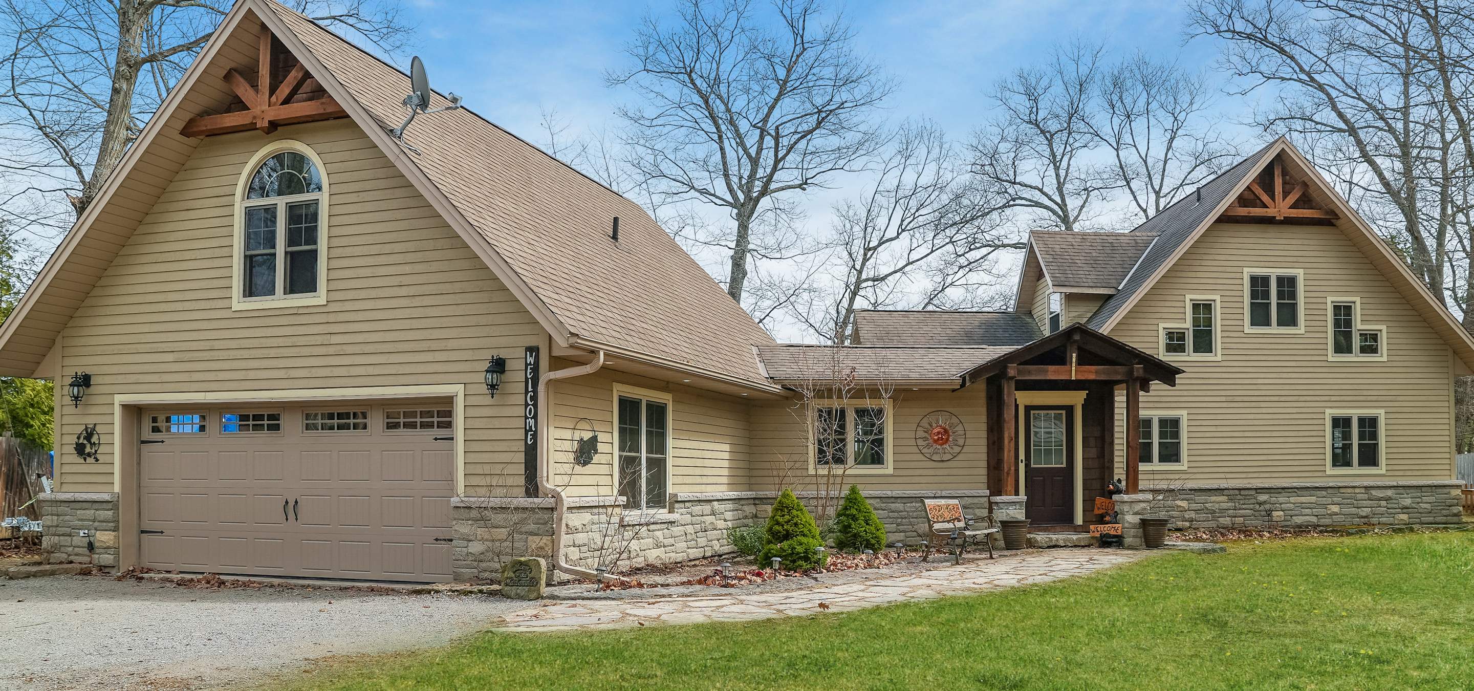property with a double car garage with green grass out front and blue sky.