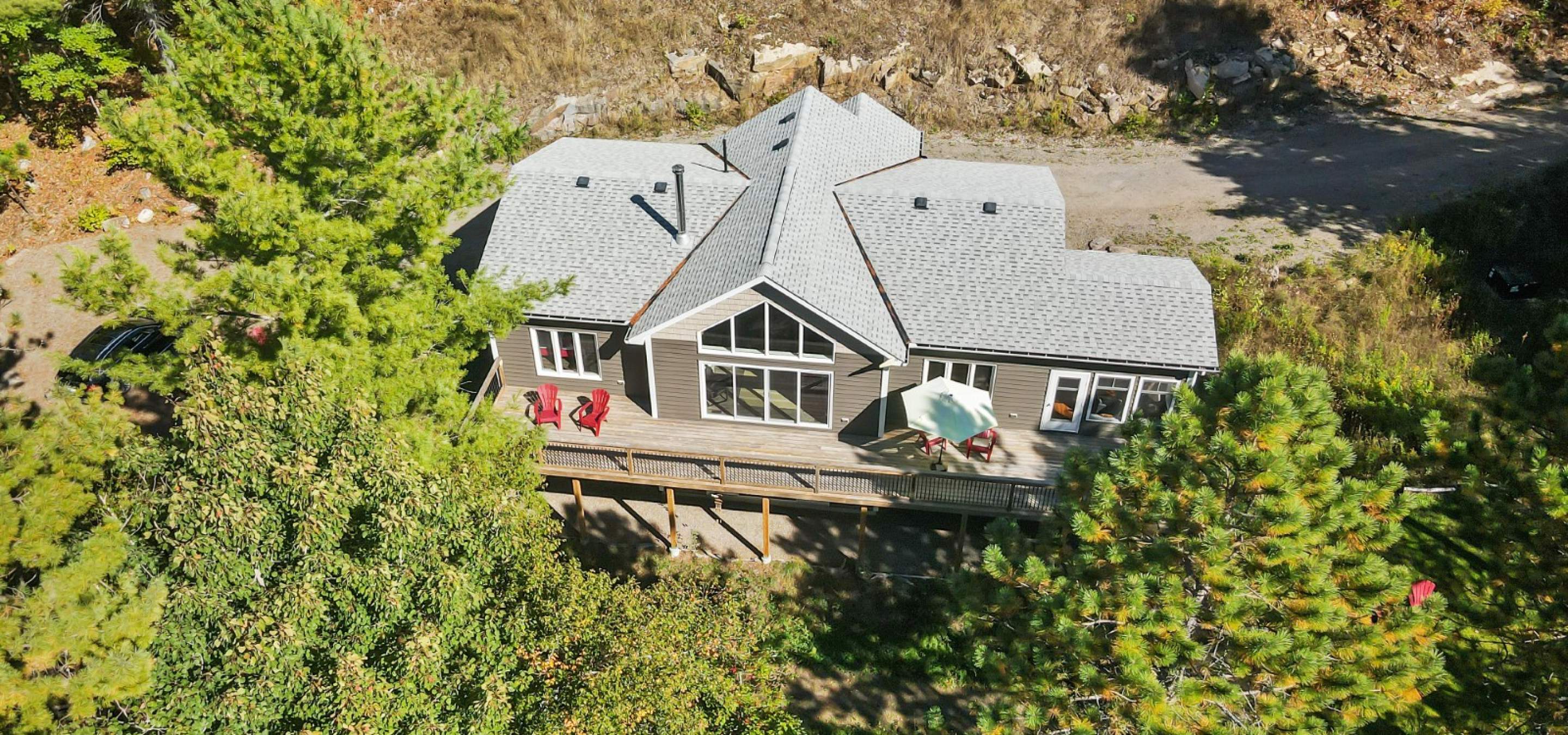 Aerial view of a cottage with large windows and trees