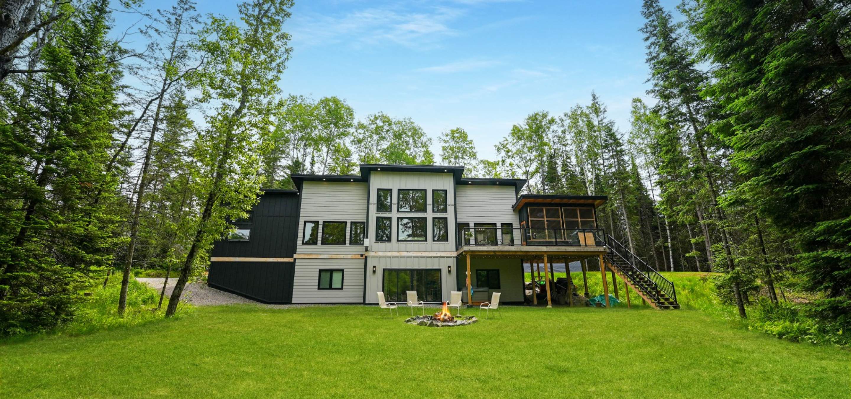 white house with green grass and 4 chairs around a firepit