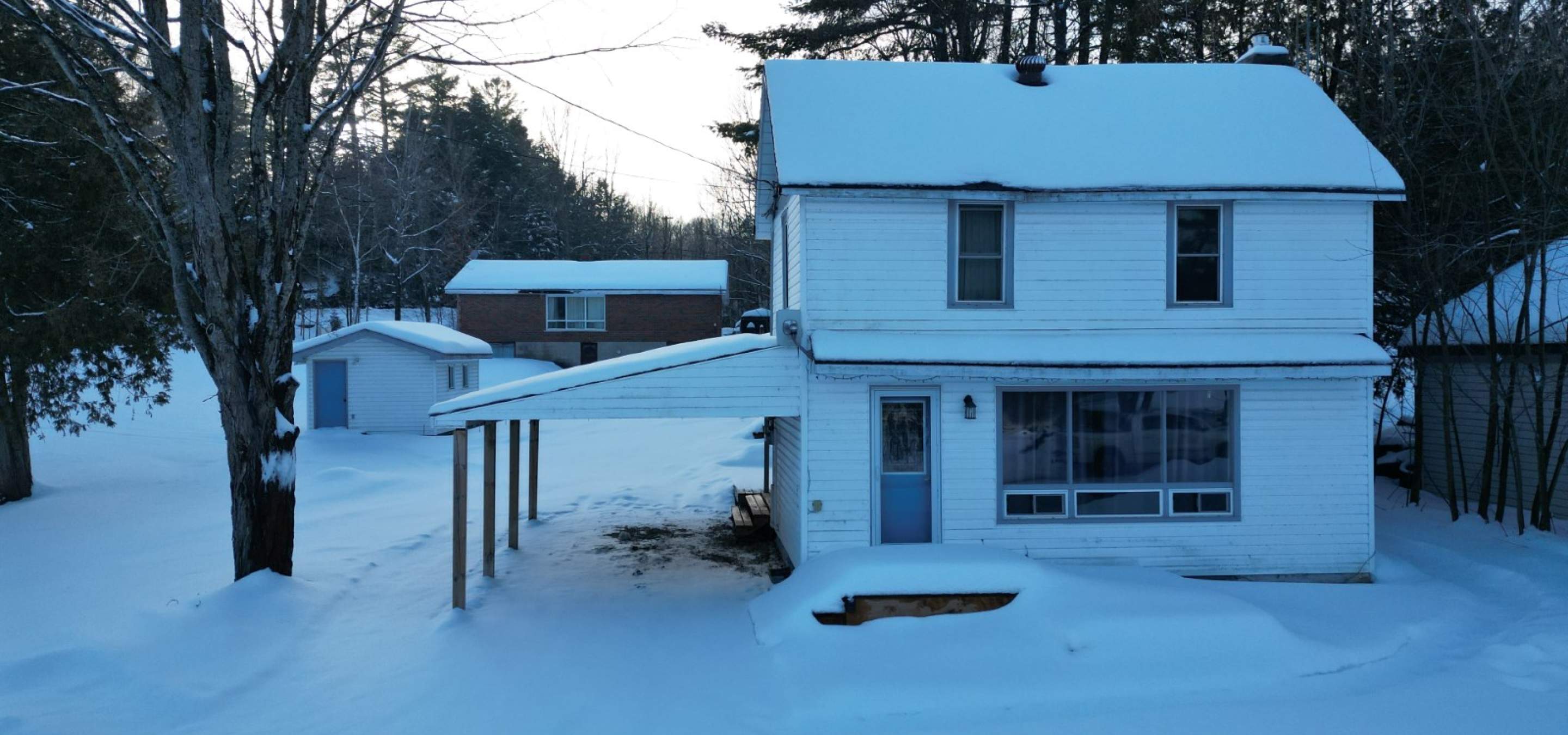 white house with carport and shed in the background