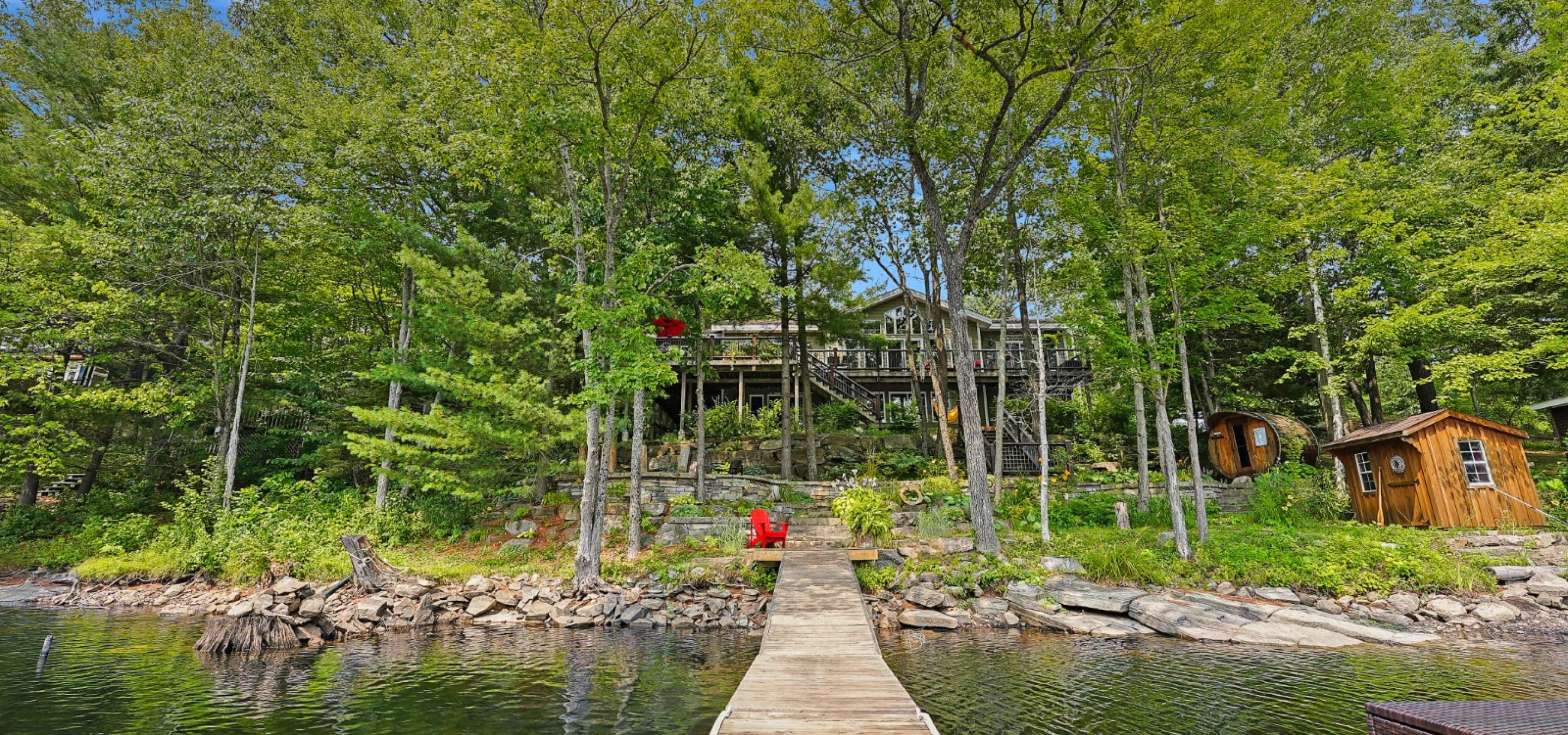 looking at a cottage from the lack, the cottage is hidden behind trees. 