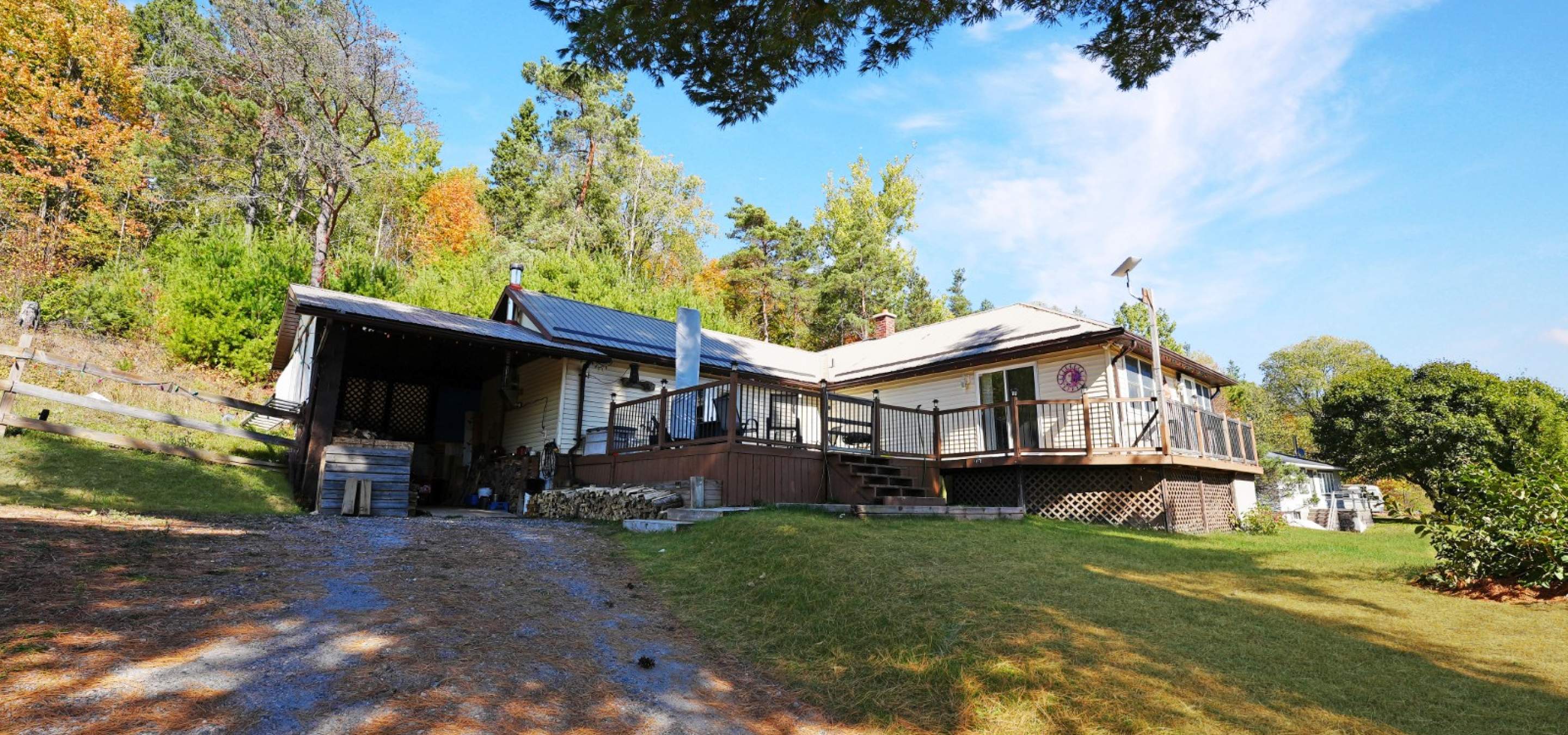 off white home with large front deck and gravel laneway