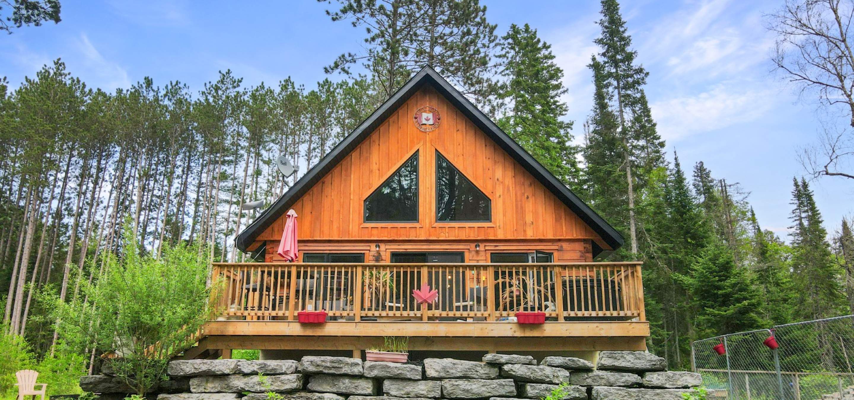 a-frame wood home with deck. Blue sky and tree behind. 