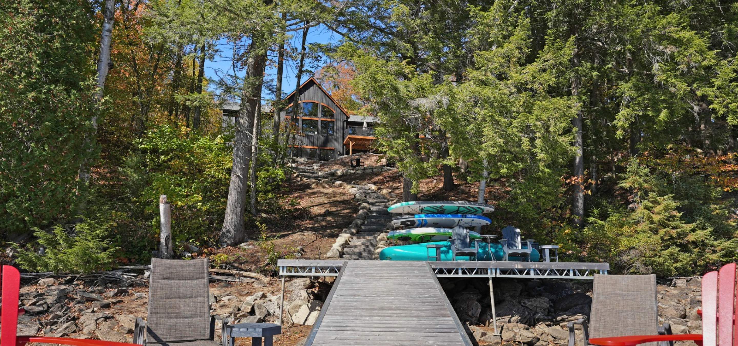 Standing on a dock looking at a Black cottage hidden by trees
