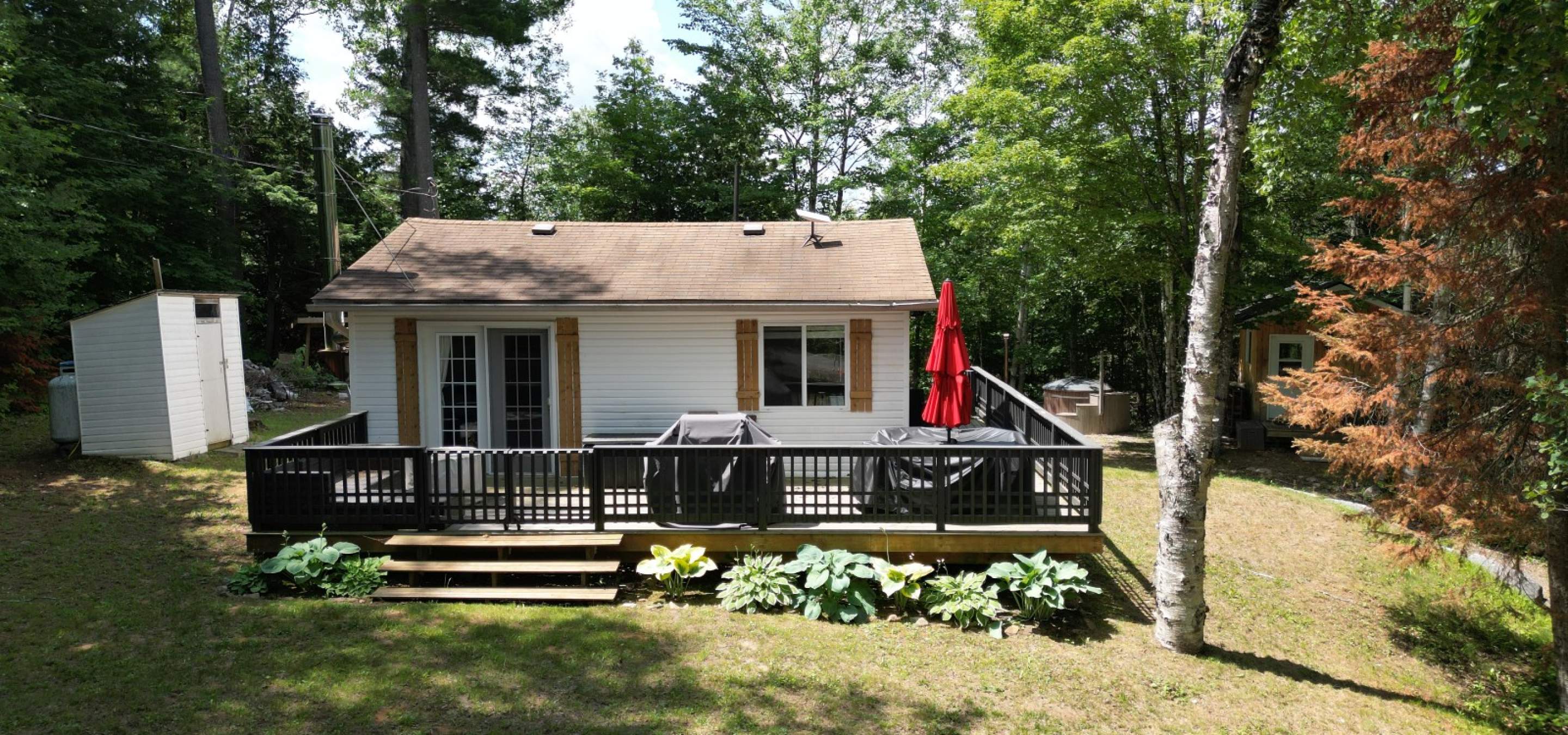 White house with a brown roof, black railing and a red umbrella