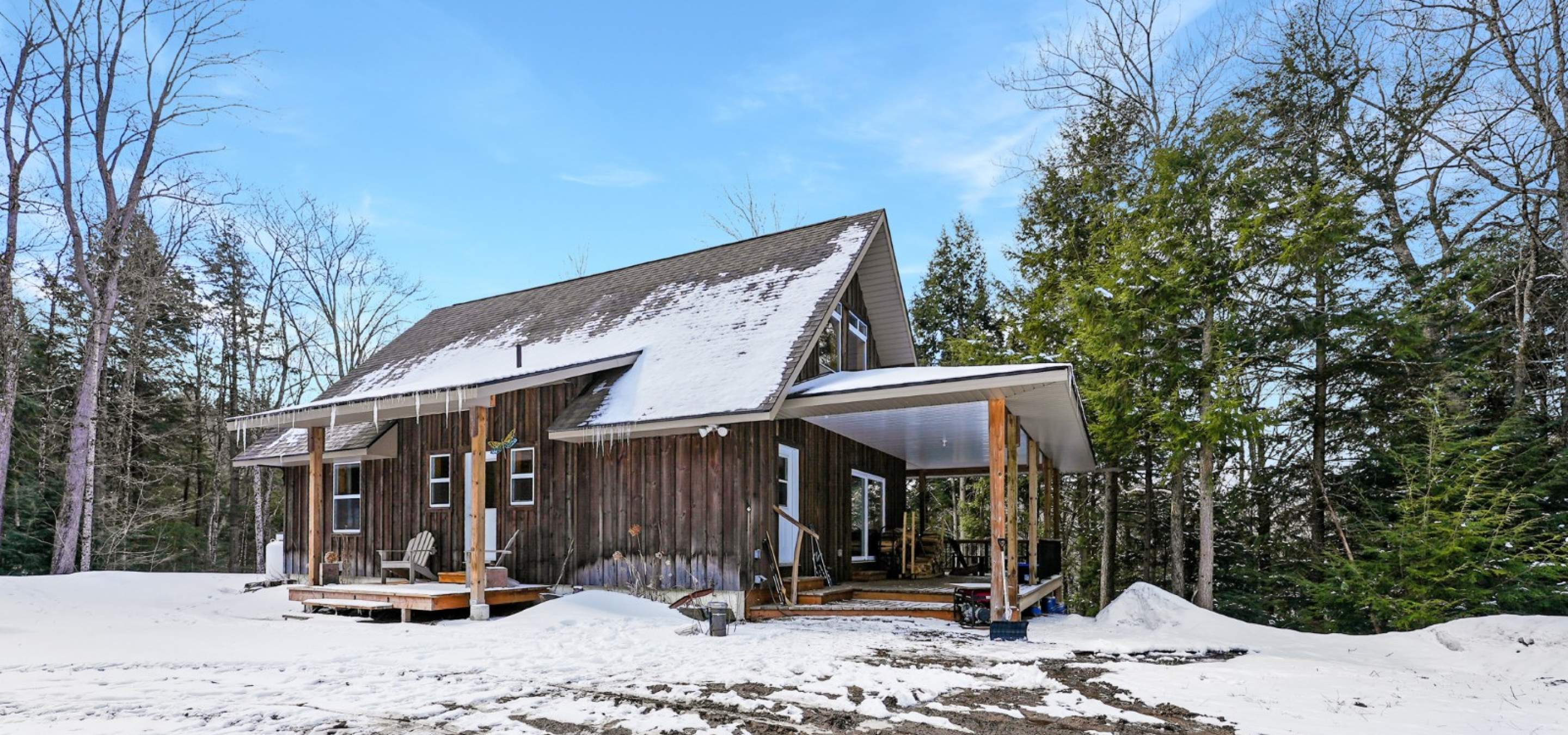 Home with 2 covered porches, trees and blue sky.