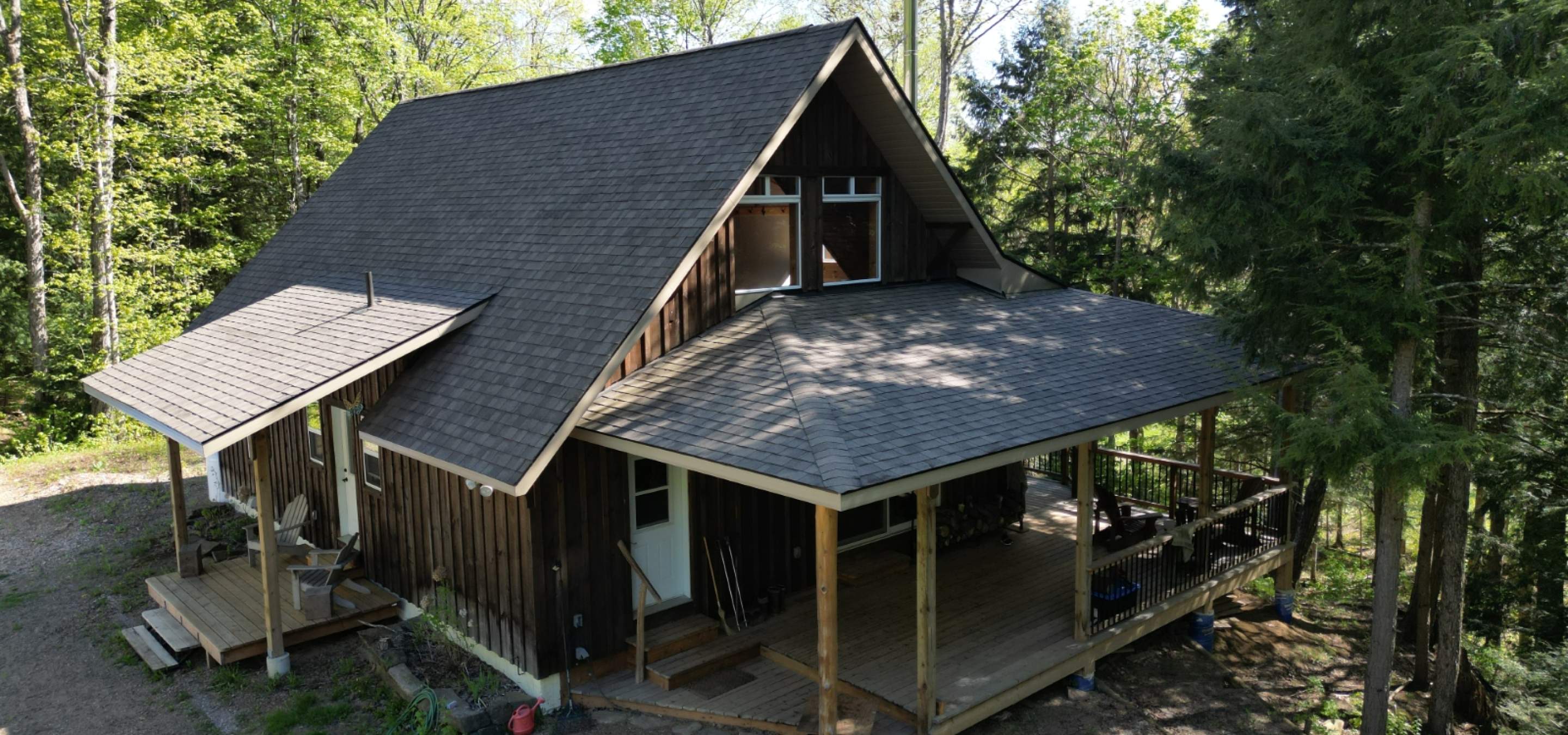 Forest home with covered porch and steep shingle roof.