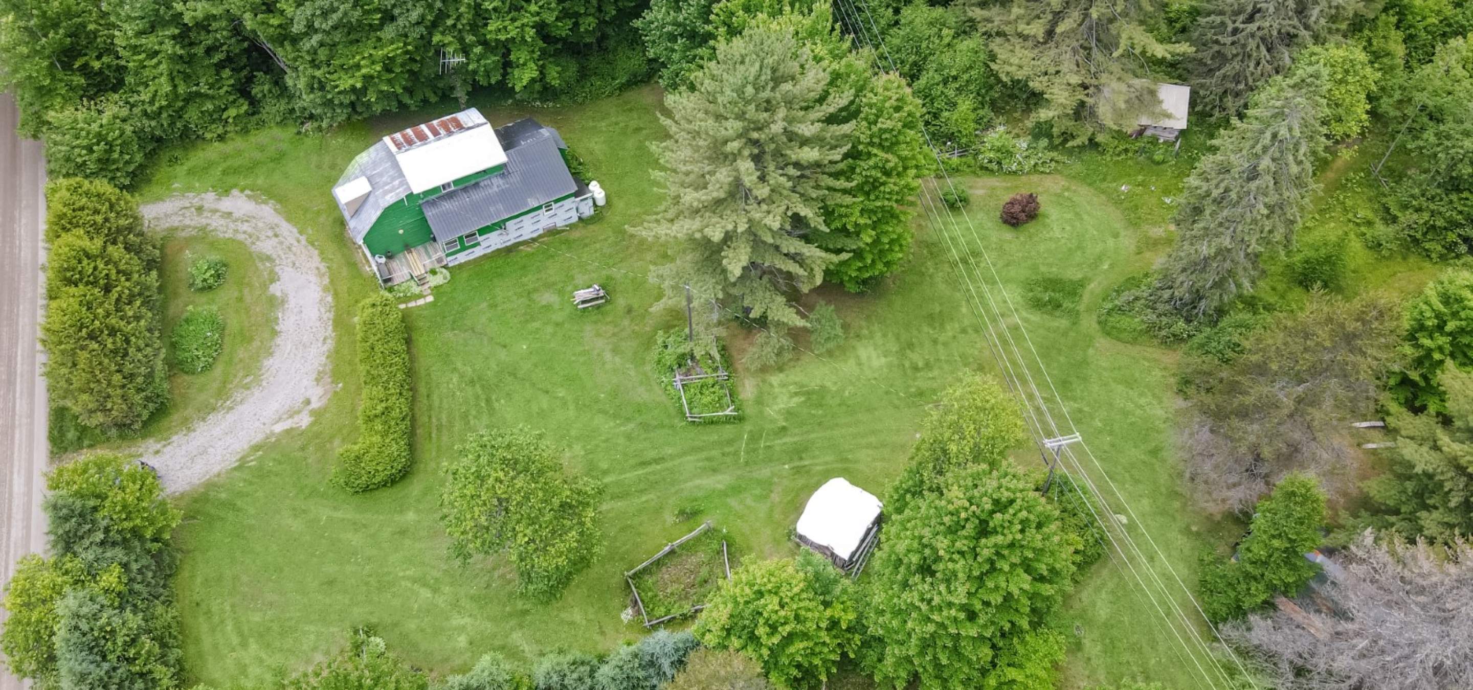 house with circular driveway. Surrounded by trees and green grass field. 