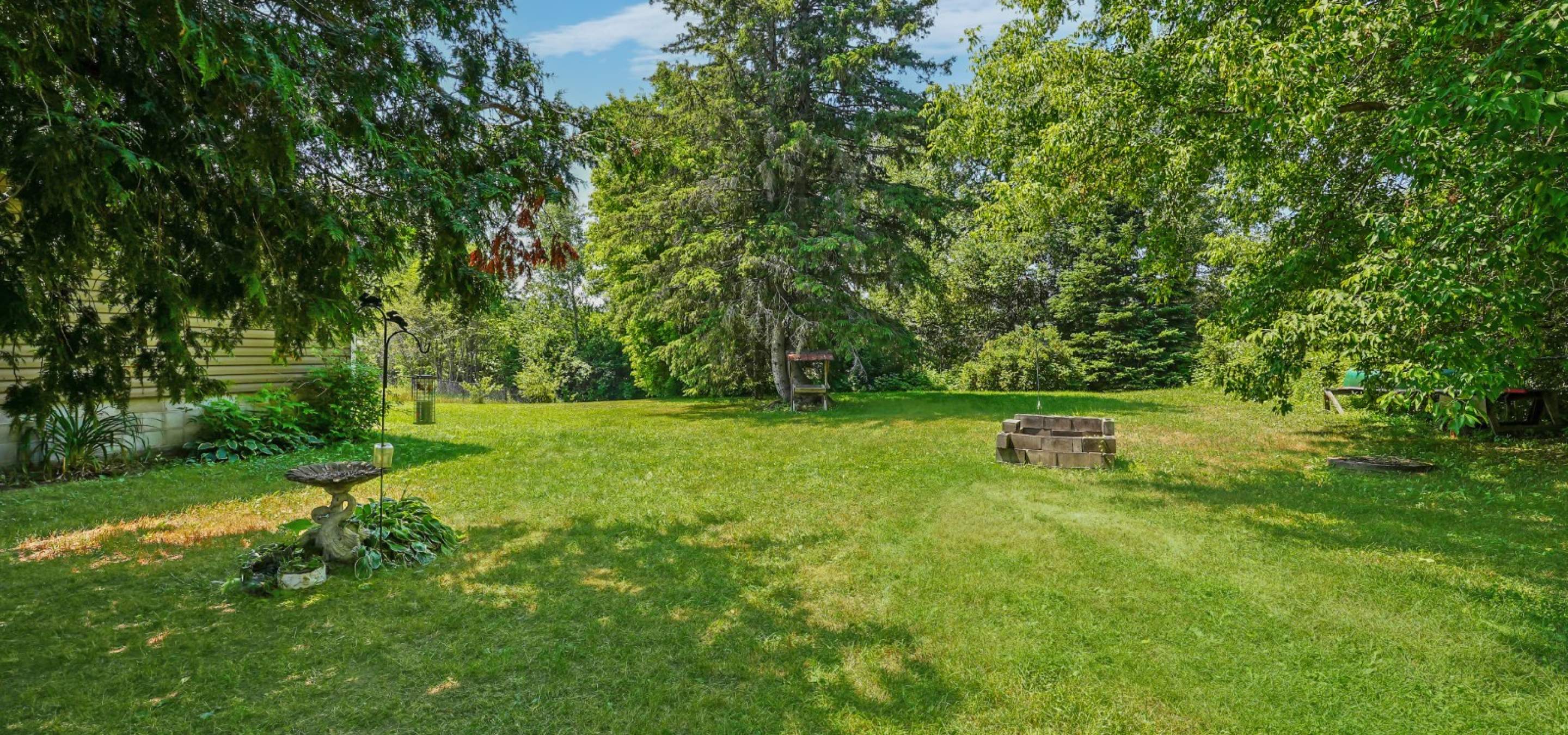 view of green grass, trees, and blue sky