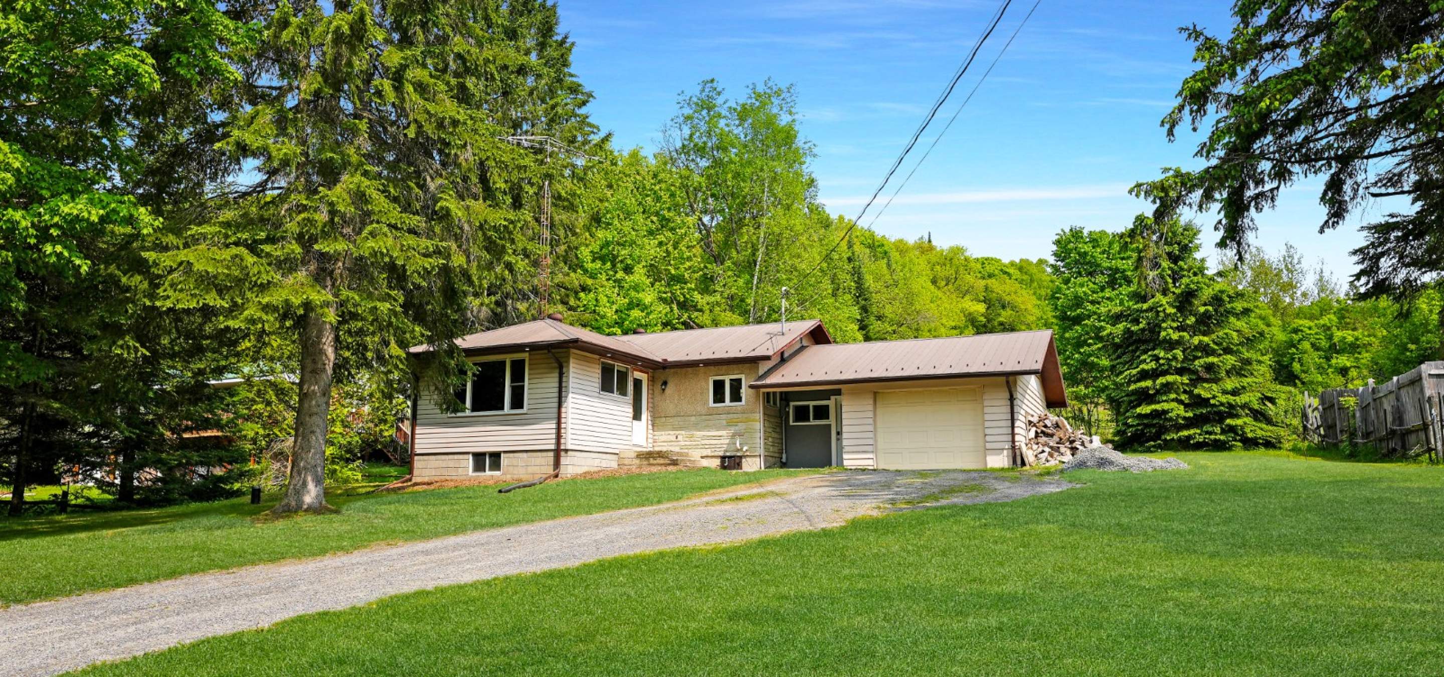 yellow home with attached single garage. with green grass and trees