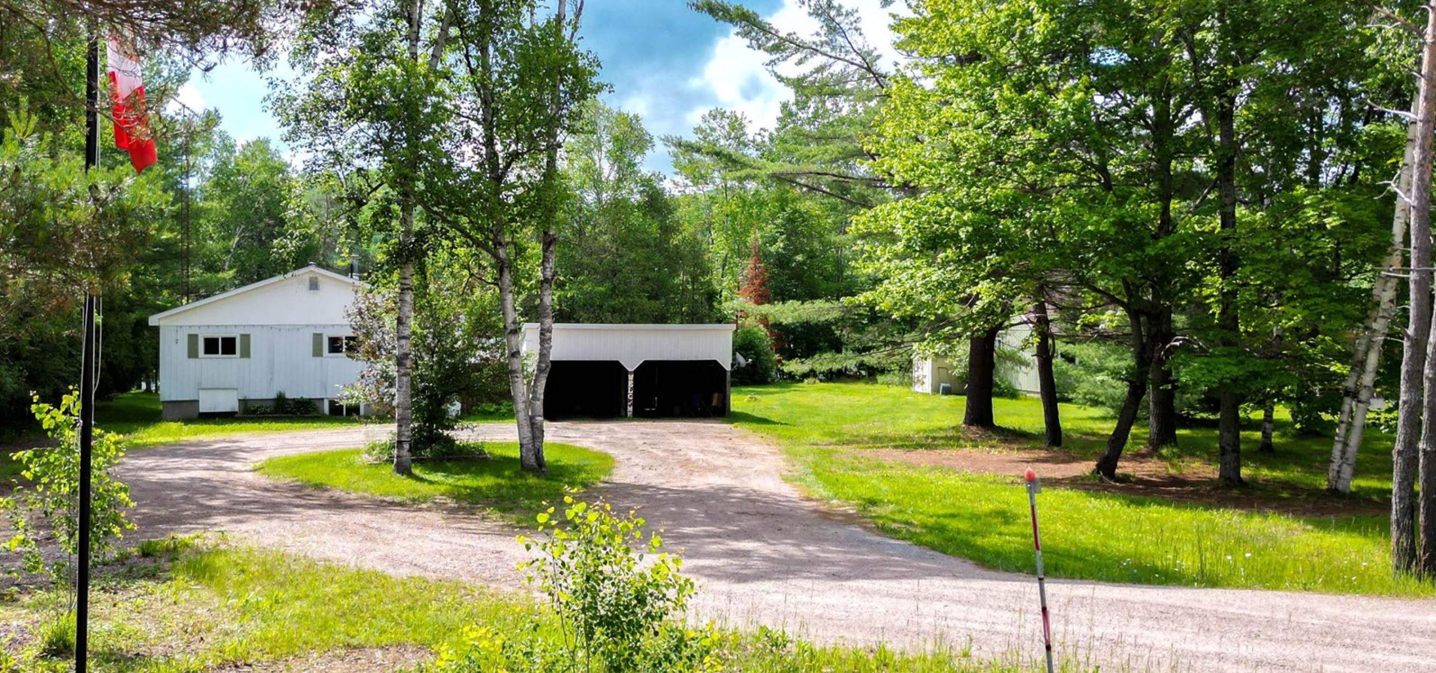 White house hidden behind trees with a gravel laneway with a turning circle around trees.