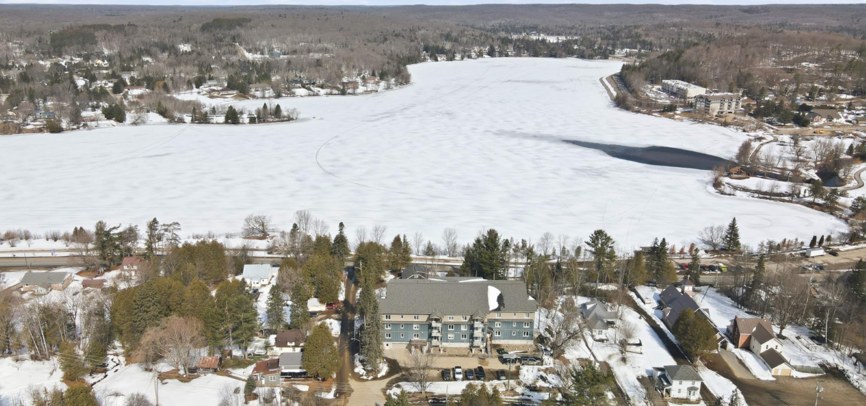 aerial view of a condo building with a frozen lake behind it. 