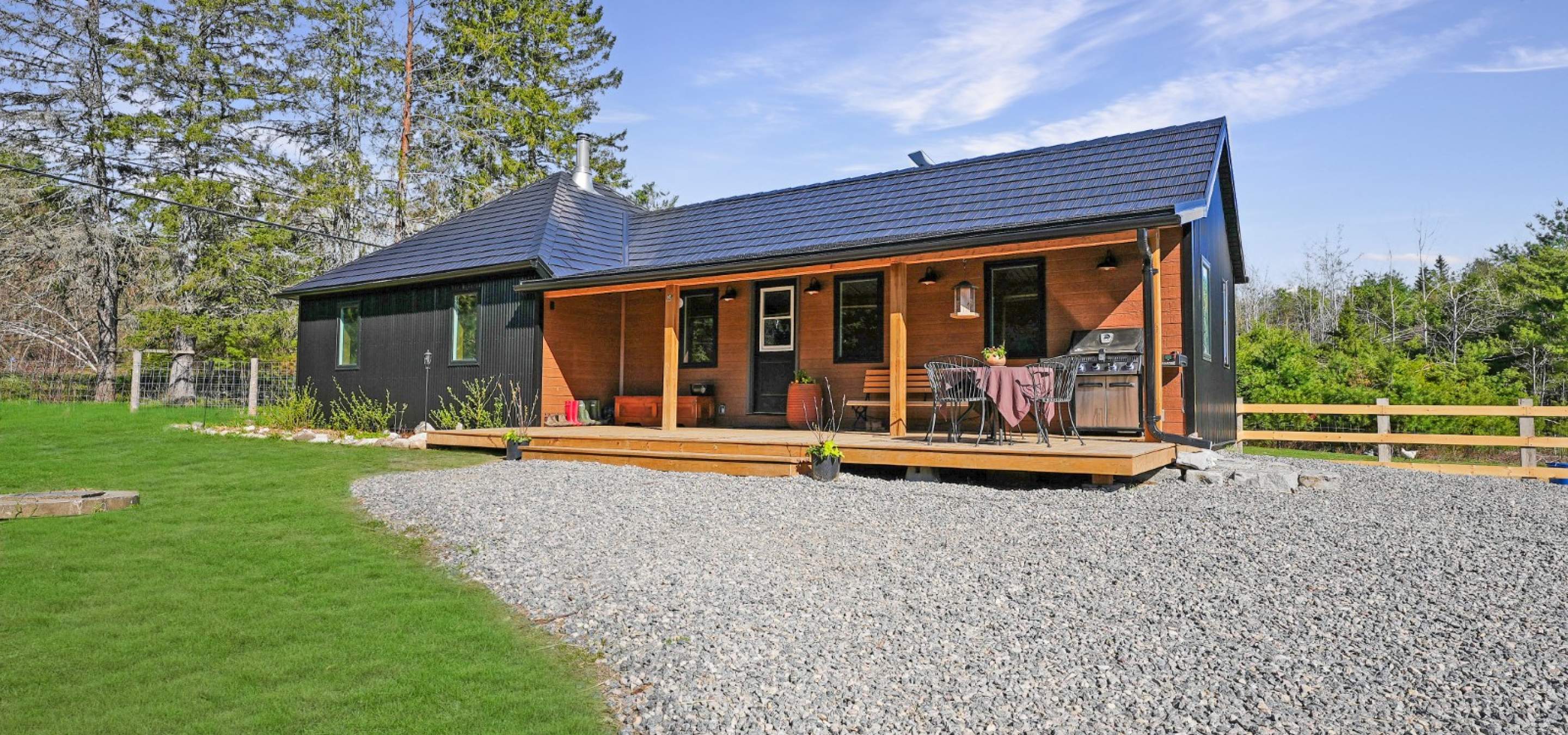 dark grey home with covered front porch and green grass out front.
