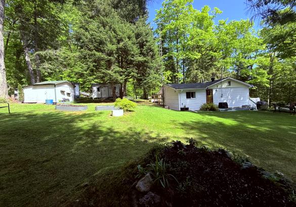 white home with white building behind, green grass and blue skies