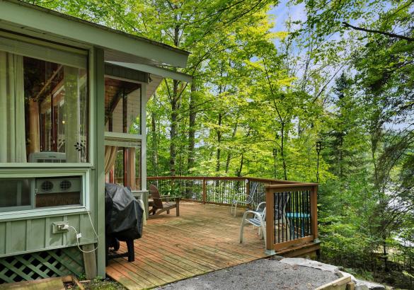 showing the view from the cottage and the deck looking towards the lake and trees