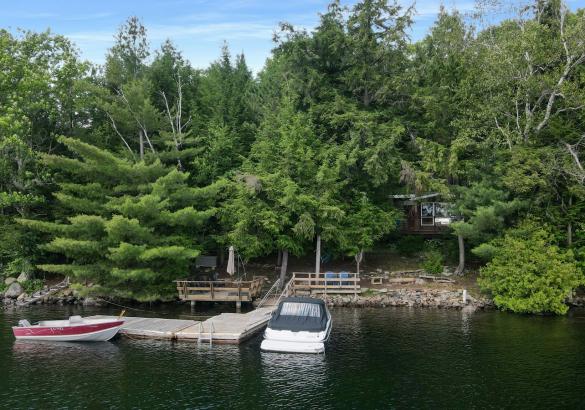 View of a cottage, dock and 2 boats from the lake.
