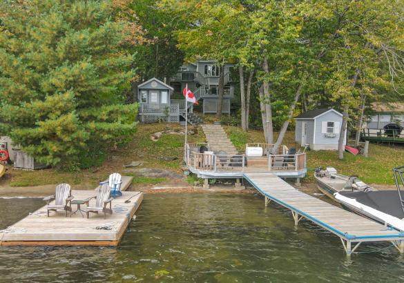 Cottage surrounded by trees with a grass lots and sandy shoreline to the lake. Patio attached with sitting & 2 docks into the lake.