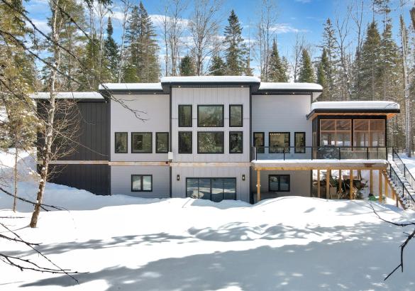 Snow covered ground, grey and black house with screened porch