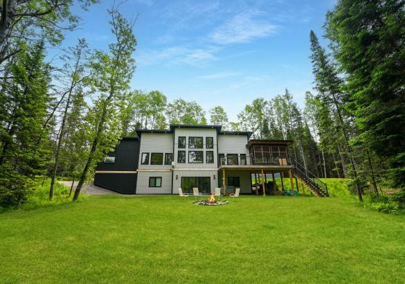 white house with green grass and 4 chairs around a firepit