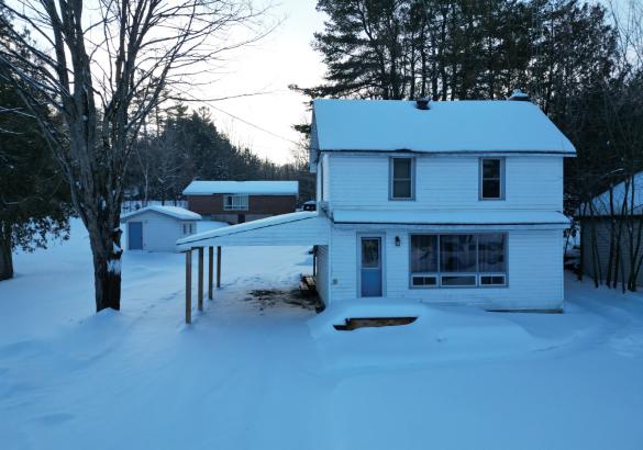 white house with carport and shed in the background