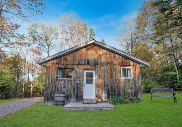 Wood cabin with green grass in front and a white door.
