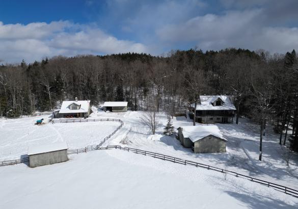 5 builds divided with fences. With trees in the background and snow covered ground. 