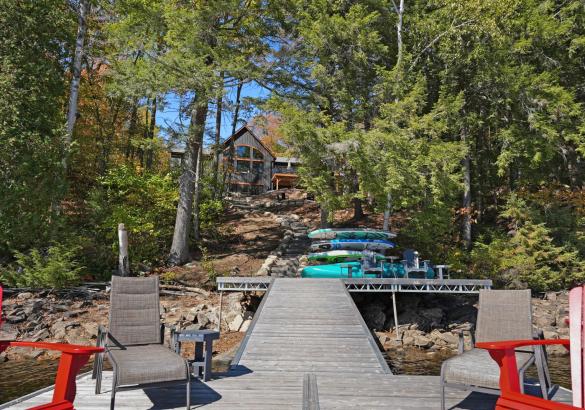 Standing on a dock looking at a Black cottage hidden by trees