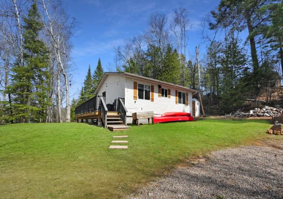 White home with red canoe, grass and stairs leading up