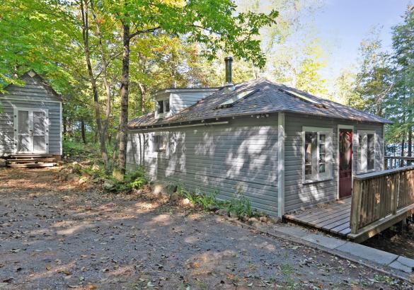 Grey cottage, red door, gravel laneway, lake in the background
