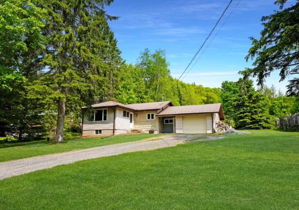 yellow home with attached single garage. with green grass and trees