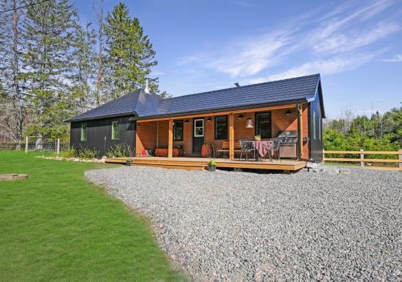dark grey home with covered front porch and green grass out front.